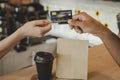 Hand customer paying with credit card for buying hot coffee cup on counter in modern cafe coffee shop Royalty Free Stock Photo