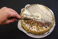 Hand cuts a cake with a knife. Tasty cake with condensed milk and poppy seeds on a black table. Royalty Free Stock Photo