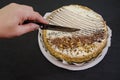 Hand cuts a cake with a knife. Tasty cake with condensed milk and poppy seeds on a black table. Royalty Free Stock Photo