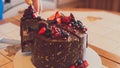 Appetizing chocolate cake decorated with strawberries, blueberries and a pomegranate on an orange background Royalty Free Stock Photo