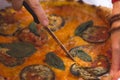 Hand cutting vegetarian pizza with knife