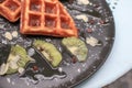 Hand cutting waffle with kiwi and ice cream on black plate. Waffle with honey. Dessert sweetness. Royalty Free Stock Photo