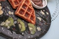 Hand cutting waffle with kiwi and ice cream on black plate. Waffle with honey. Dessert sweetness. Royalty Free Stock Photo