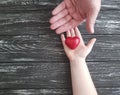 Hand dad and child give heart red on black wooden