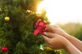 Hand decorating a chirstmas tree with red ribbon and present box