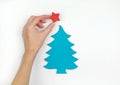 A hand decorating little wooden christmas tree with a star, white background. Flat lay. Top view. Royalty Free Stock Photo