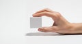 a hand delicately holding a small white square object against a plain neutral and softly shaded background Royalty Free Stock Photo