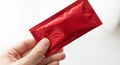 Hand holding red foil packet close-up macro shot isolated on Royalty Free Stock Photo