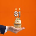 The hand that delivers cupcake with the number 81 candle - Birthday on orange background