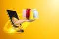 Hand delivers packages through smartphone screen on yellow background. Concept for online shopping, business, stay at home