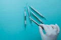 Hand of a dentist in a latex glove taking dental tools on a blue background.