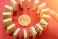 Hand destroying Circle row of Dominoes with the golden bitcoin in the center