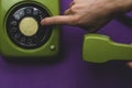 Hand dials a number on a classic phone with round dial. vintage green telephone with handset Royalty Free Stock Photo