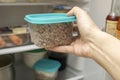 A hand of a dieting woman taking a plastic container with cooked buckwheat from a frige, freezer, losing weight concept Royalty Free Stock Photo