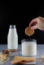 Hand dipping biscuit cracker in a glass of milk. Children's breakfast or snack. Baking and eating concept.