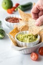 Hand dipping a homemade Keto tortilla chip into a bowl of guacamole.