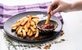 Hand dipping a potato chip into tomato ketchup top view Royalty Free Stock Photo