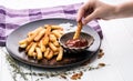 Hand dipping a potato chip into tomato ketchup top view