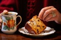 a hand dips a slice of panettone in a cup of coffee