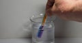 Hand dips a test strip into a solution in a beaker