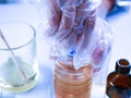 Hand discovers hazardous chemicals. A chemist mixes a yellowish substance. Work in the laboratory Royalty Free Stock Photo