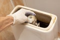 hand dismantling the flush mechanism of the toilet tank