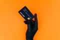 Hand in a disposable black glove with a bank card. Contactless payment of the invoice for purchases by the client during covid-19 Royalty Free Stock Photo