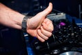 Hand of DJ shows the class background of switchers and remote control in nightclub