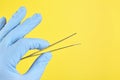 Hand of doctor in blue medical glove holding a tweezers isolated on yellow background Royalty Free Stock Photo