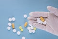 Hand of a doctor holding a bunch of pills on a blue surface