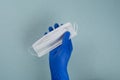 The hand of a doctor, nurse or scientist in blue gloves holds a medical mask for protection against infection isolated on a gray- Royalty Free Stock Photo