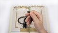 Hand Doing Dhikr with Prayer Beads Above Holy Quran Royalty Free Stock Photo