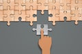Hand drag The last piece of jigsaw puzzle concept for solution and completion. grey background, wooden pieces Royalty Free Stock Photo