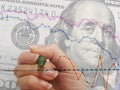 Hand drawing a chart to depict stock market movement, with dollar bill in the back