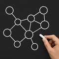 Hand drawing a conceptual network diagram on a blackboard using a piece of white chalk stick Royalty Free Stock Photo