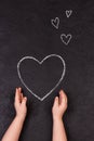 Hand drawing heart with chalk. Cute little girl with symbol of love. Royalty Free Stock Photo