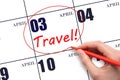 Hand drawing a red circle and writing the text TRAVEL on the calendar date 3 April. Travel planning.