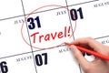 Hand drawing a red circle and writing the text TRAVEL on the calendar date 31July. Travel planning. Royalty Free Stock Photo