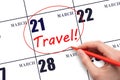 Hand drawing a red circle and writing the text TRAVEL on the calendar date 21 March. Travel planning.
