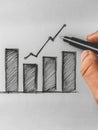Hand drawing an upward bar graph sketch symbolizing growth.