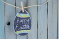 Hand drawn Easter egg, chalk on chalkboard with greeting hanging from twine by clothespin Royalty Free Stock Photo