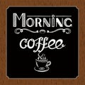Hand drawn lettering `Morning coffee` with charcoal effect and view of a cup of coffee on black and brown wood background.