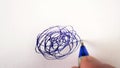 Hand drawn tangle scrawl drawn on paper with blue pen in circular motion scribble shape.