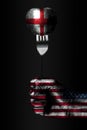 A hand with a drawn USA flag holds a fork, on which is a ball with a drawn England flag, a sign of influence, pressure, grip and