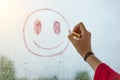 Hand draws a positive smiley on a rainy autumn window Royalty Free Stock Photo