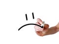 Hand draws sad smiley with black marker on transparent whiteboard