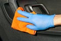 Hand of driver in blue protective glove is wiping with a cloth an interior handle of car door. Coronavirus or Covid-19 car