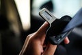 Hand of driver holding seat belt safety belt lock in car.