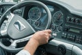 Hand of a driver on steering wheel at intercity coach bus. Focus on steering wheel. Blurry control panel buttons and dials on the Royalty Free Stock Photo