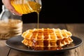 hand drizzling honey on a fresh belgian waffle